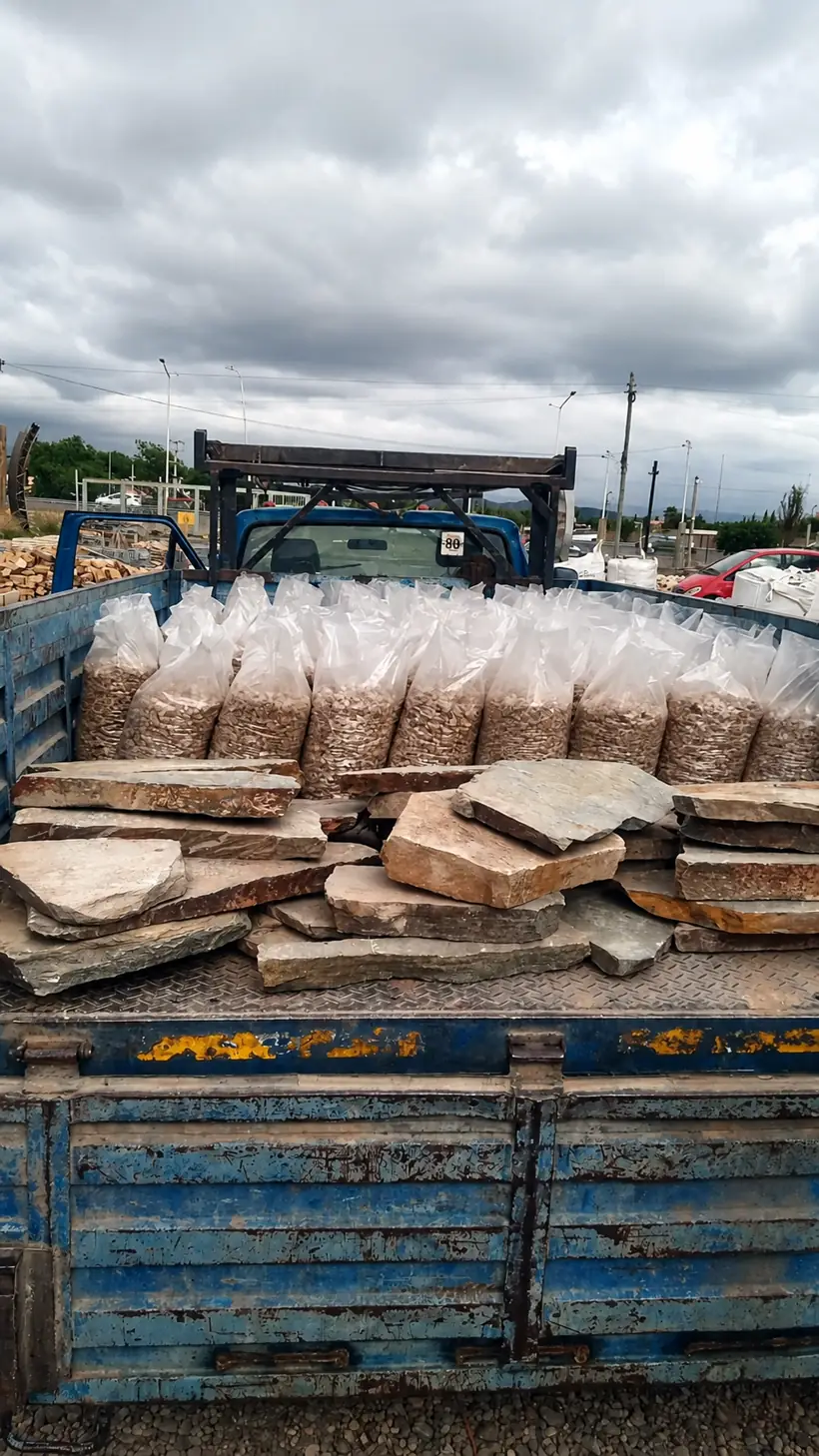 Piedra laja y bolsas de canto rodado estibadas sobre la caja.